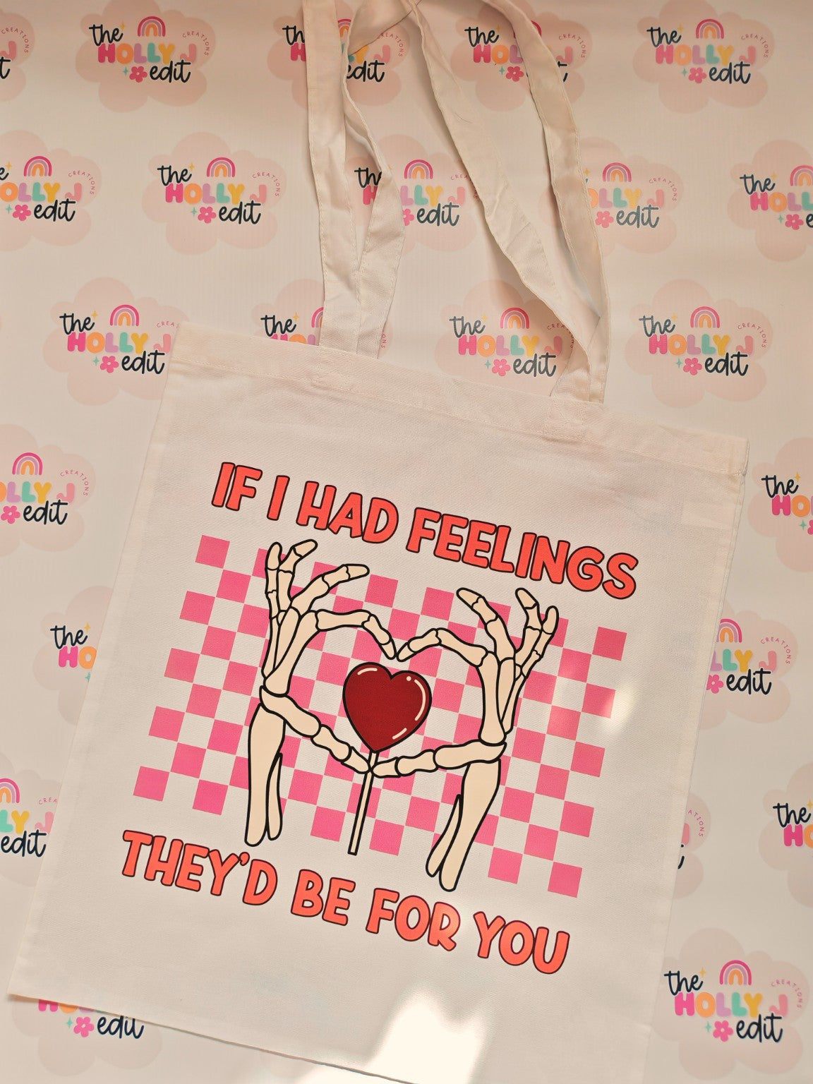 White cotton tote bag with skeleton hands forming a heart and pink checkerboard design