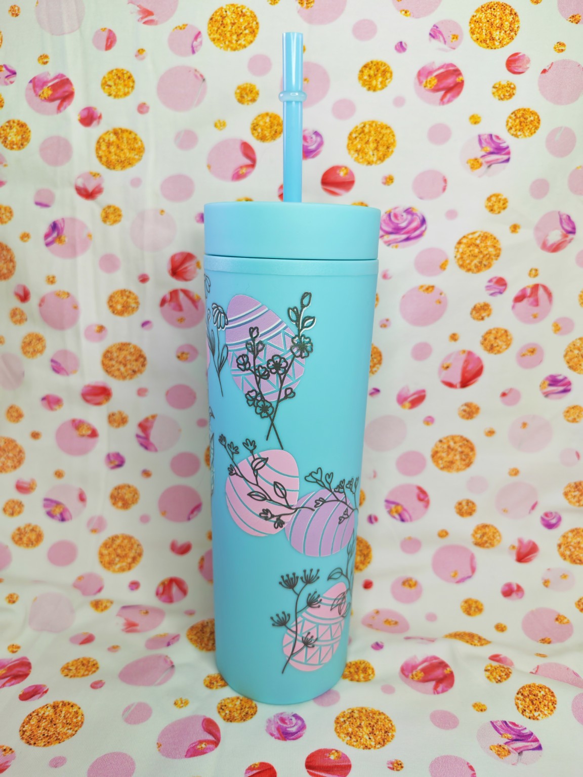Blue 16oz skinny tumbler with pink Easter egg and floral design, with straw