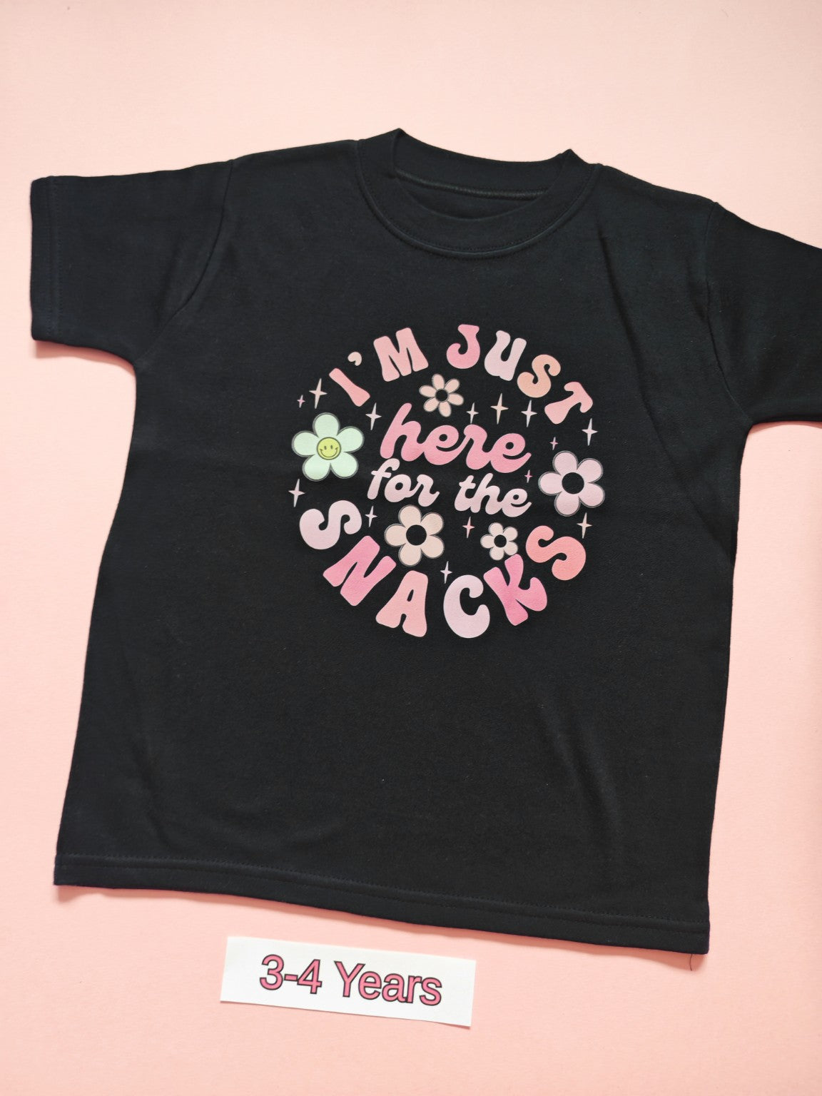 Black children's T-shirt with pastel floral I'm just here for the snacks design, size 3-4 years