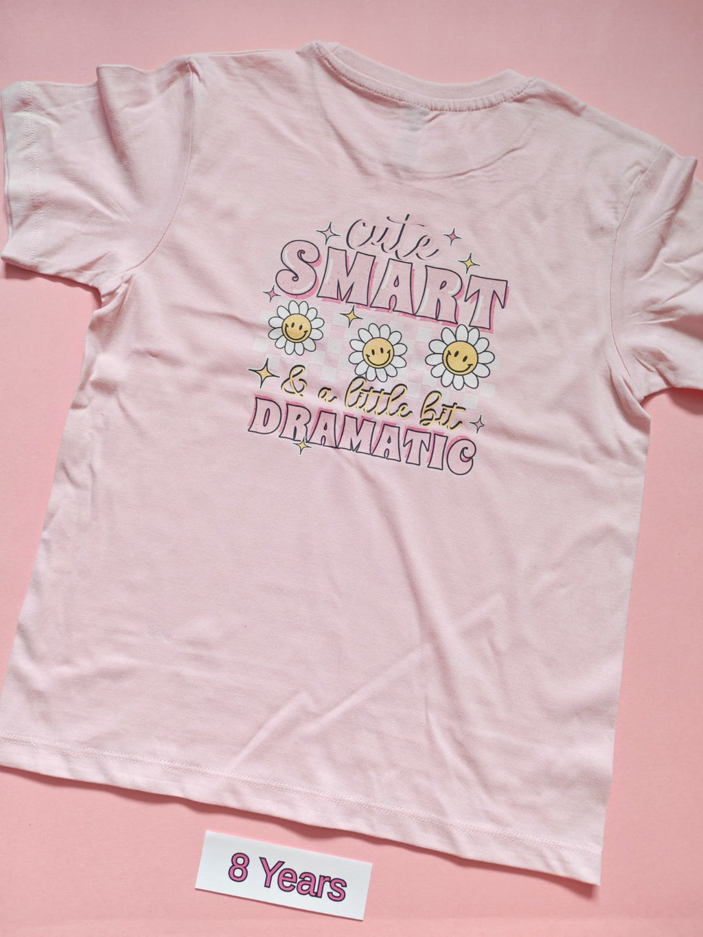 Pale pink children's T-shirt with Cute Smart and a Little Bit Dramatic daisy design, back, size 8 years