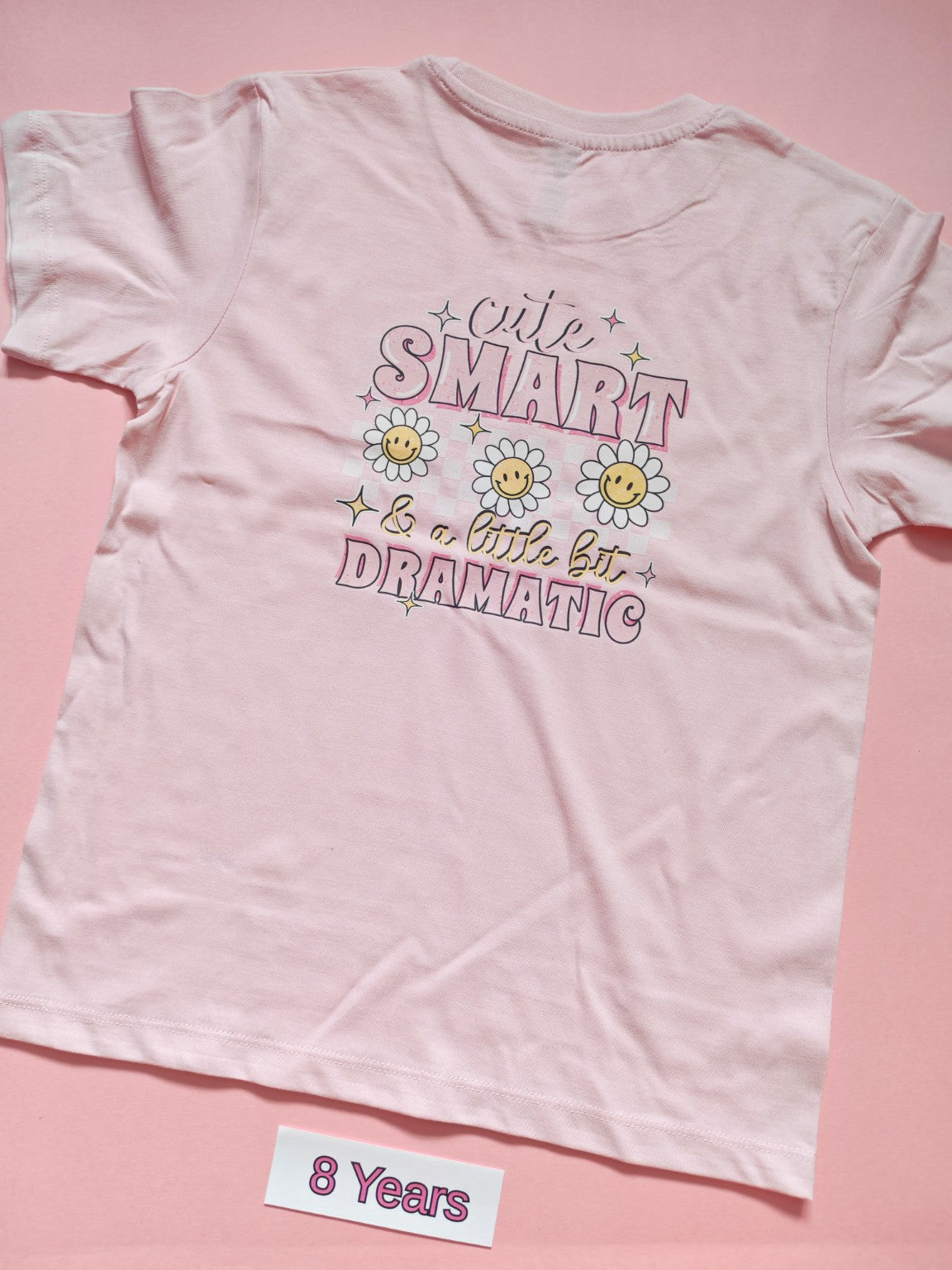 Pale pink children's T-shirt with Cute Smart and a Little Bit Dramatic daisy design, back, size 8 years