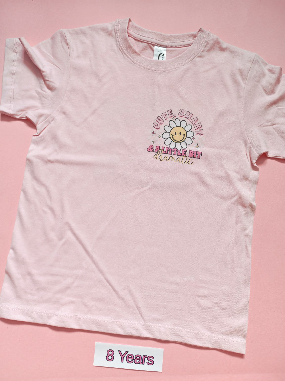 Pale pink children's T-shirt with Cute Smart and a Little Bit Dramatic daisy design, front, size 8 years