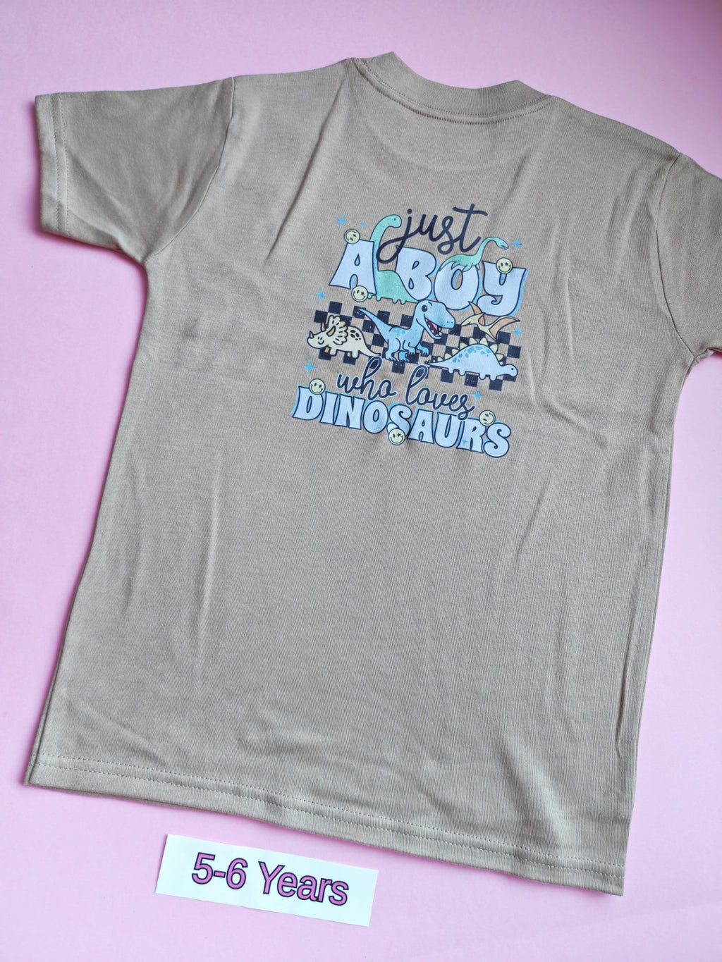Back of taupe children's dinosaur t-shirt with blue dinosaur design, 5-6 years