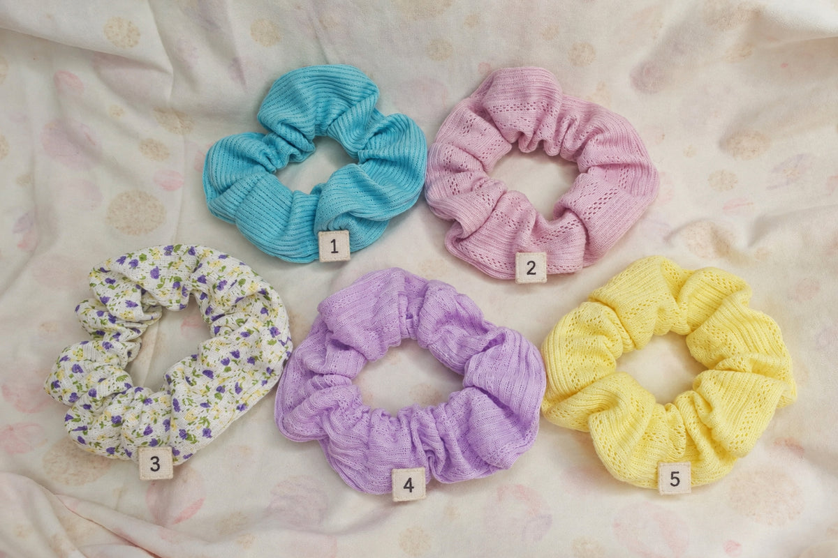 Five handmade pastel fabric scrunchies in blue, pink, floral, lilac and yellow