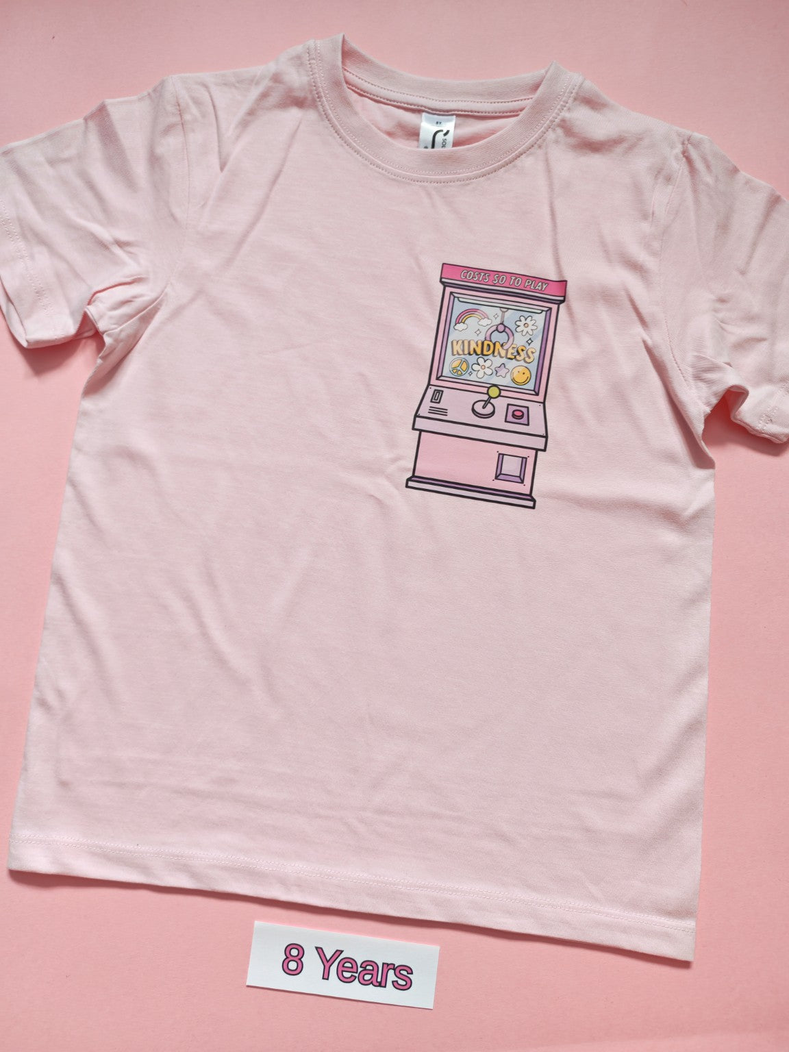 Pale pink children's T-shirt with Kindness claw machine design, size 8 years
