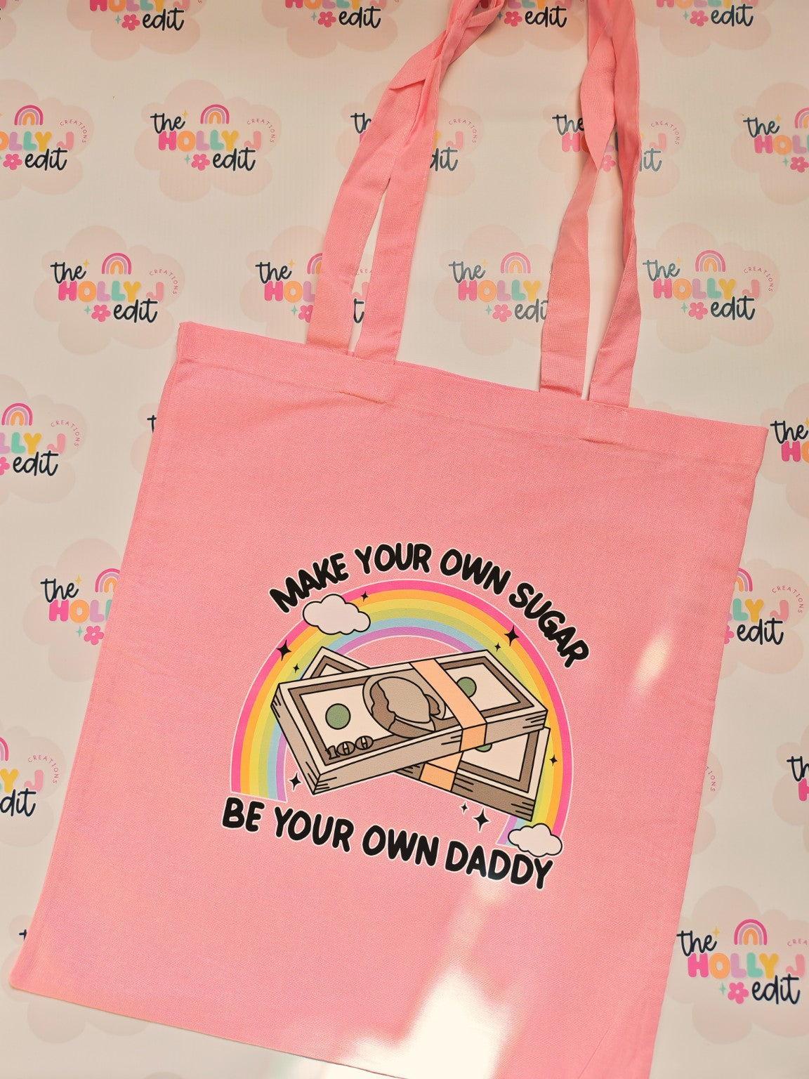Pink cotton tote bag with colourful rainbow and money design reading Make Your Own Sugar Be Your Own Daddy