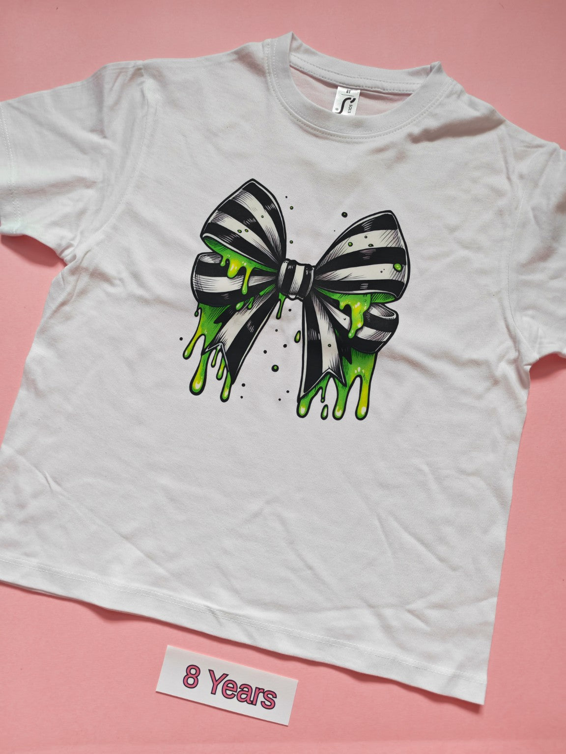 White children's T-shirt with black and white striped bow dripping with green slime, size 8 years