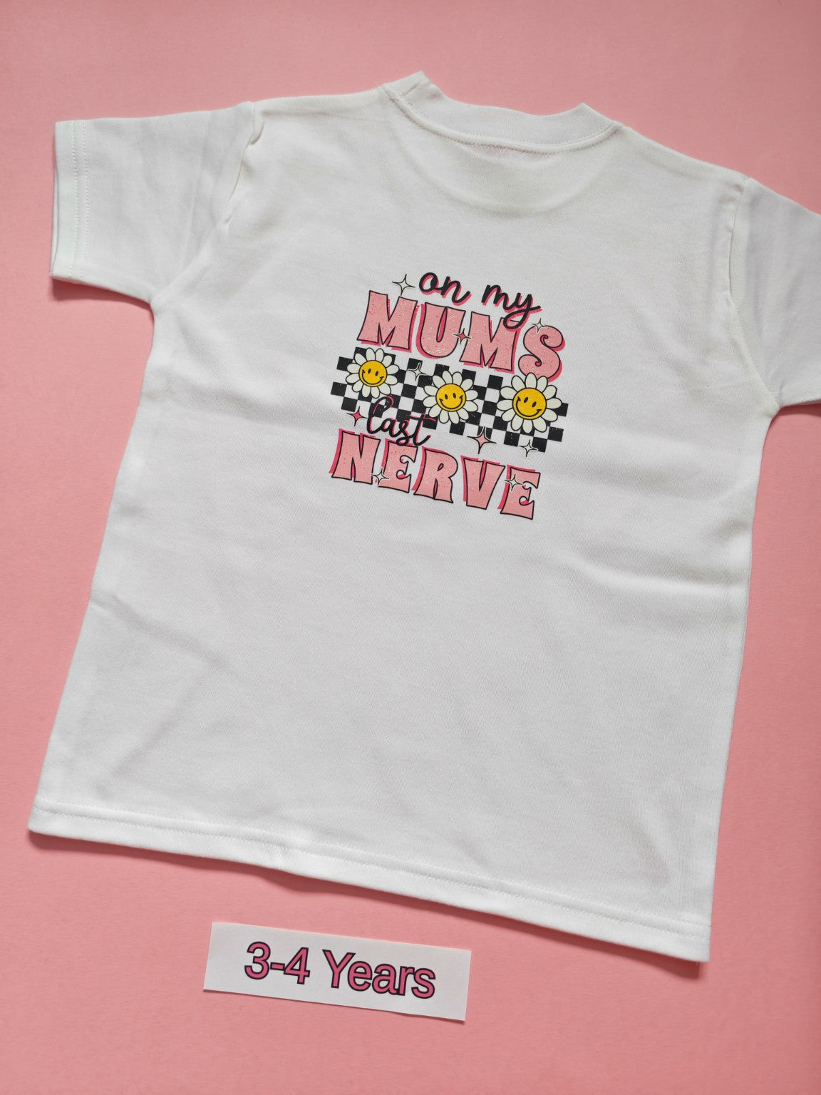 White children's T-shirt back with pink daisy and checkerboard On My Mum's Last Nerve design, size 3-4 years