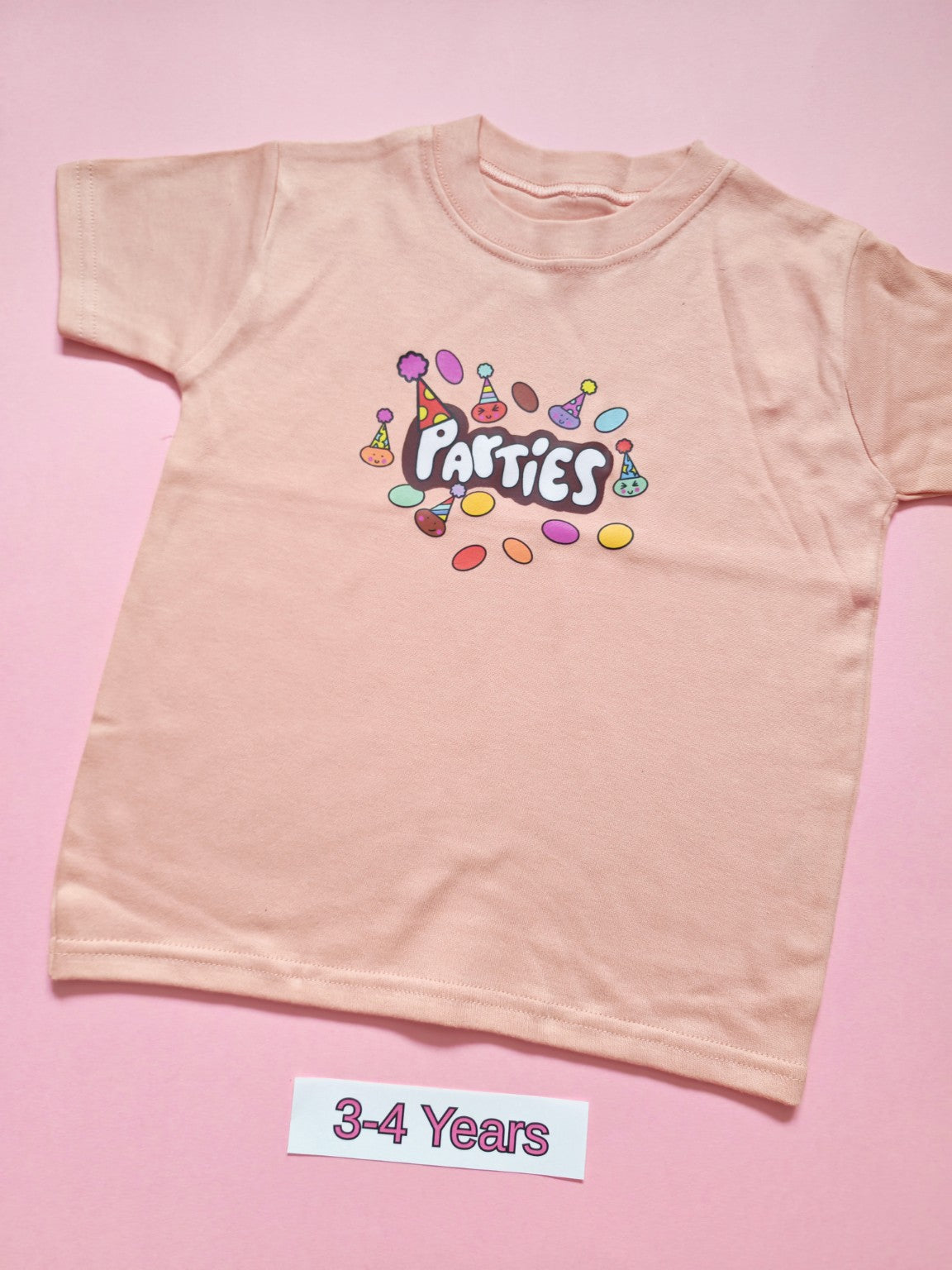 Pastel pink children's T-shirt with colourful Parties party hat design, size 3-4 years