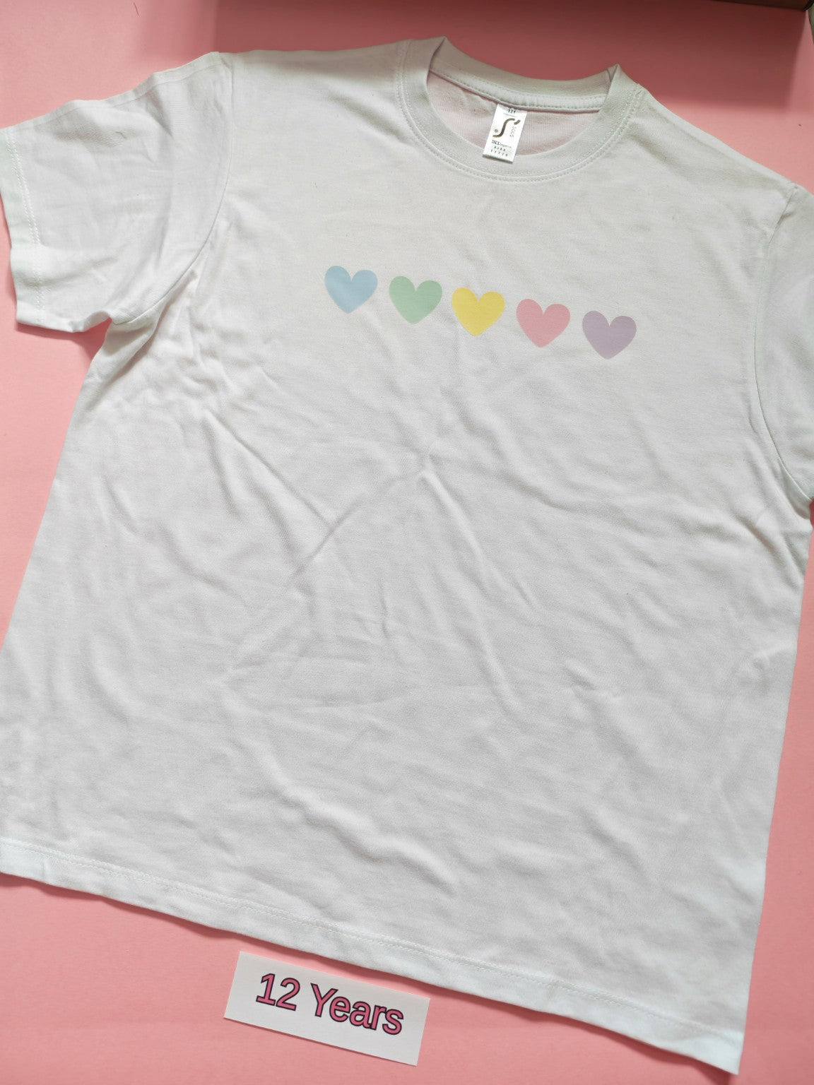 White children's T-shirt with pastel rainbow hearts design, size 12 years