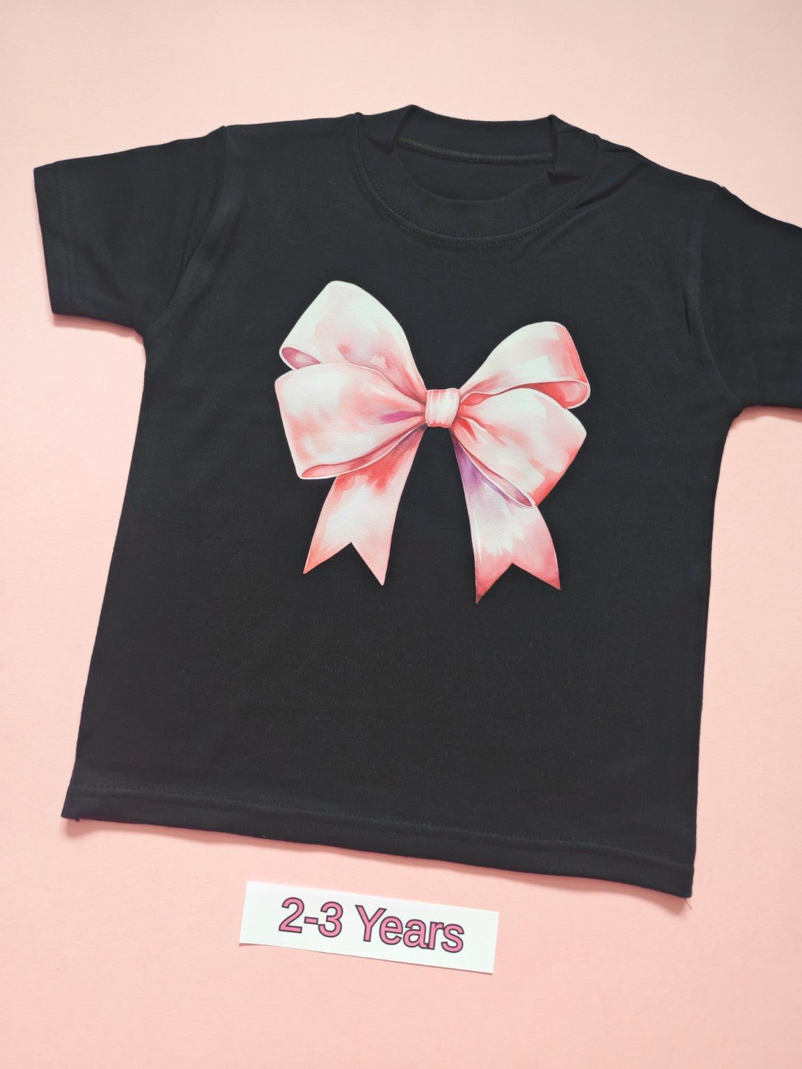 Black children's T-shirt with large pink bow design, size 2-3 years