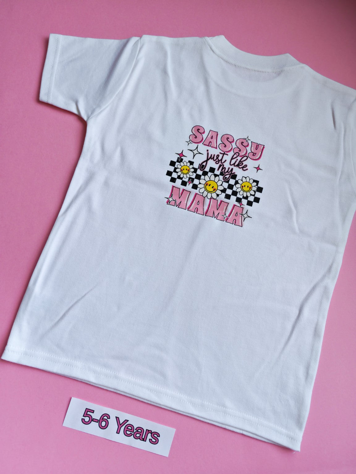 White children's t-shirt with pink Sassy Just Like My Mama daisy and checkerboard design on the back, 5-6 years